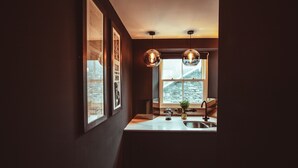A kitchen with a window, pendant lights, and a sink. - The Rockefeller Apartments (Windermere)
