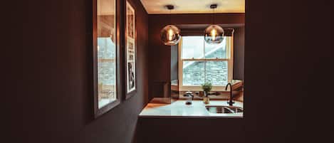 A kitchen with a window, pendant lights, and a sink.