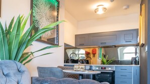 A modern living room with a tufted sofa, a round coffee table, and a large potted plant. - The Rockefeller Apartments (Windermere)