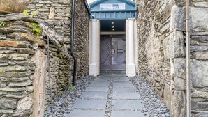 A stone pathway leading to a building entrance with a sign reading "Rockefeller." - The Rockefeller Apartments (Windermere)