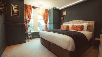 Een slaapkamer met een groot bed, een raam met gordijnen, een dressoir en een kroonluchter.