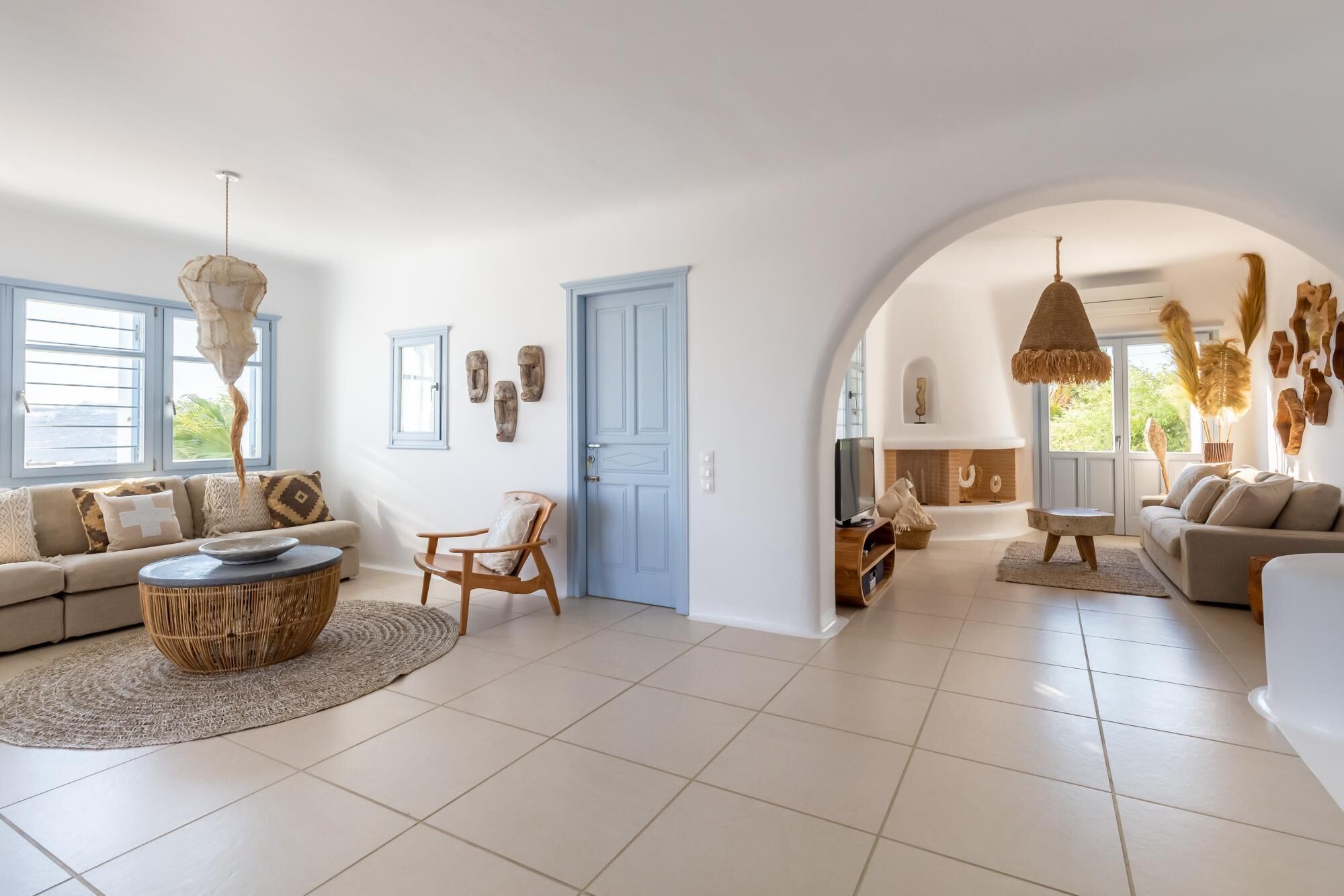 A spacious living area with a large arched doorway, a fireplace, and a television. There are two sofas and a coffee table.