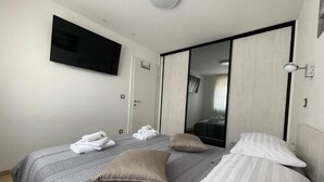 Ett hotellrum med en säng, en tv som är monterad på väggen, en garderob och en spegel.