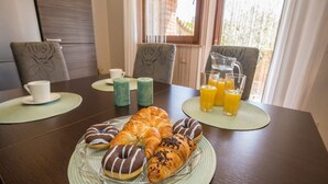 A breakfast setting with croissants, donuts, and orange juice on a table. - Apartment Andre Poreč - Two Bedroom Apartment with Terrace and Pool (Nova Vas)