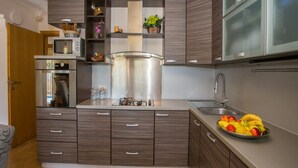 A modern kitchen with built-in appliances, wooden cabinets, and a fruit bowl on the counter. - Apartment Andre Poreč - Two Bedroom Apartment with Terrace and Pool (Nova Vas)