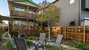 A two-story house with a balcony, a wooden fence, and a garden area with chairs and a table. - Tremont  1BR  Pet Friendly, Private w/dedicated workspace and soaking tub! (Cleveland)