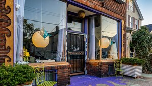 A brick building with large windows, a purple awning, and a door with a metal gate. - Tremont  1BR  Pet Friendly, Private w/dedicated workspace and soaking tub! (Cleveland)