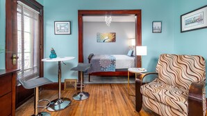 A room with a bed, a chair, a small table, and a window with blinds. - Tremont  1BR  Pet Friendly, Private w/dedicated workspace and soaking tub! (Cleveland)