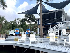 A deck with white lounge chairs and a staircase leading to a building with large windows. - 🛥️🛥️Boat House in Weeki Wachee-10 minute easy paddle to main river (Spring Hill)
