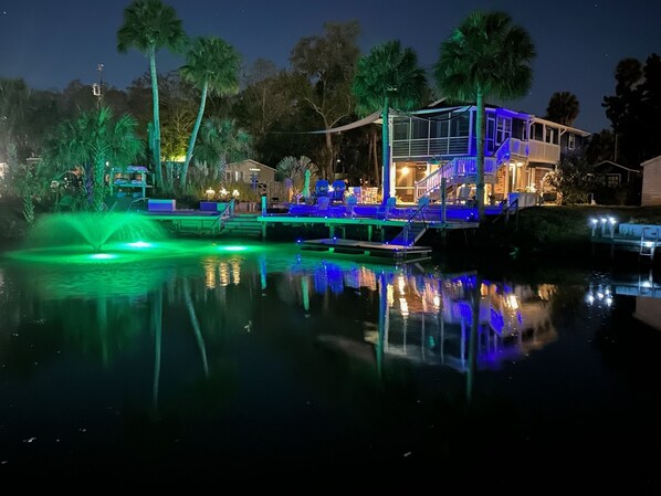 A waterfront property with a pool, palm trees, and a lit-up deck area. - 🛥️🛥️Boat House in Weeki Wachee-10 minute easy paddle to main river (Spring Hill)