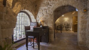 Une pièce aux murs de pierre, avec un bureau en bois, une chaise et une table sur laquelle se trouve une lampe.