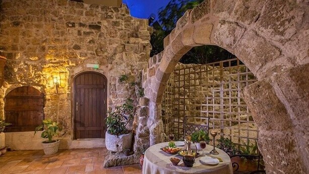 Un espace extérieur aménagé pour les repas, avec des murs en pierre, une porte en bois et des plantes en pot.