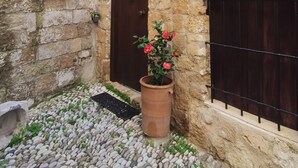 Un bâtiment en pierre avec une porte en bois, un pot de fleurs et une enseigne sur laquelle on peut lire « Porolithos ».