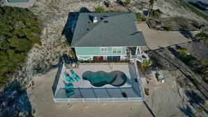 Une propriété située en bord de mer, dotée d’une piscine, d’une terrasse couverte et d’une grande maison.