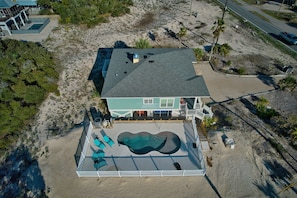 Une propriété située en bord de mer, dotée d’une piscine, d’une terrasse couverte et d’une grande maison.