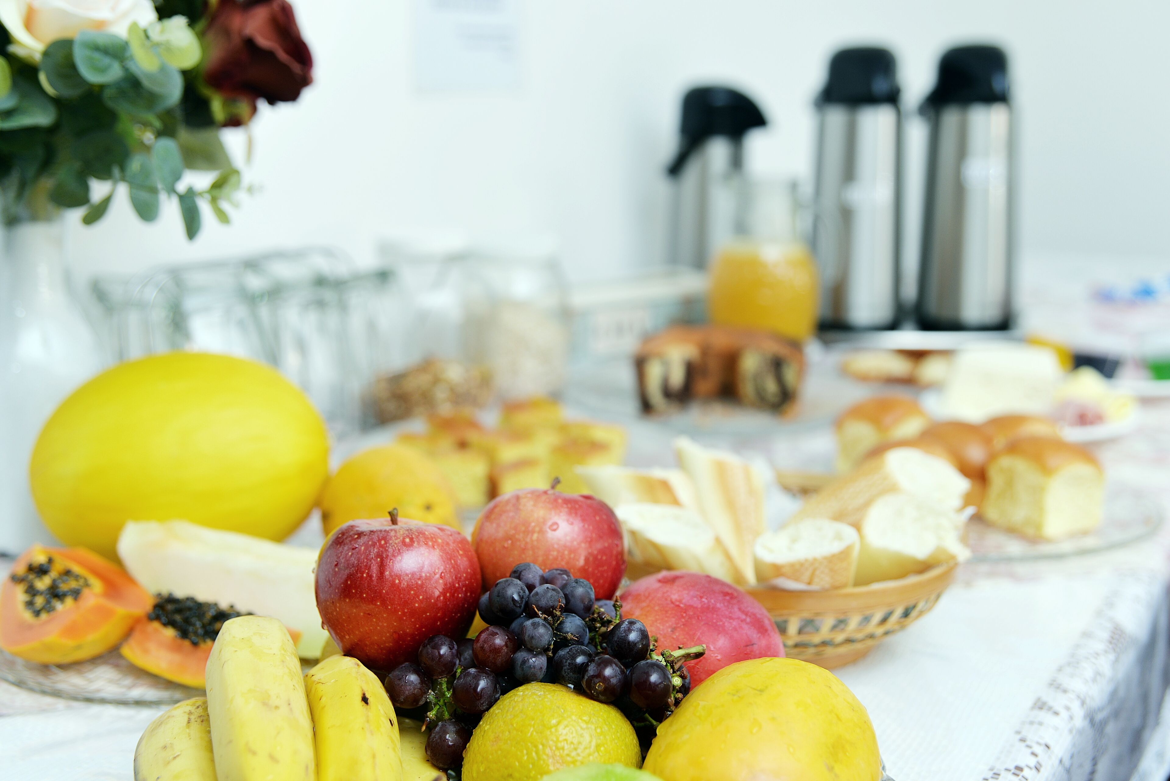 Una mesa de desayuno con frutas, pan y bebidas.