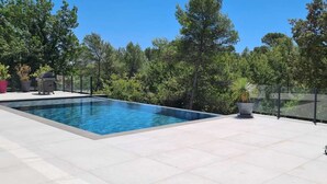 A rectangular swimming pool with a tiled deck, surrounded by a fence and trees. - Apartment in the heart of Provence on a magnificent golf course (Flassans sur issole)