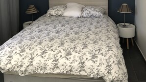 A bedroom with a bed, two bedside lamps, a headboard, and a curtain. - Apartment in the heart of Provence on a magnificent golf course (Flassans sur issole)