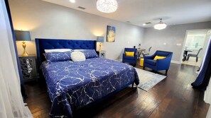 Una camera da letto con un letto grande, due poltrone, una scrivania e un lampadario.