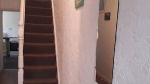 Een trap die leidt naar een plateau met een structuurwand en een lijst met een afbeelding.