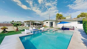 Une piscine avec des chaises longues, un patio couvert et une vue sur l’océan.