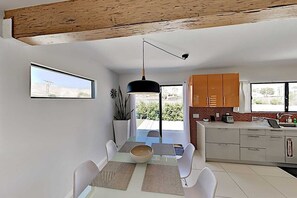 A modern kitchen with white cabinets, a black pendant light, and a view of the outdoors through the window. - Private Oasis: Cozy Villa Minutes from Downtown Palm Springs, 2 min from golf cs (Palm Springs)