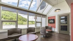 Un hall d’hôtel doté de grandes fenêtres, d’un comptoir d’accueil et d’espaces aménagés avec des sièges.