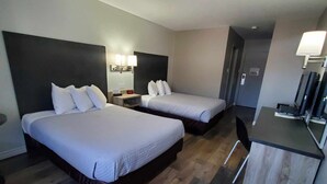 Une chambre d’hôtel avec deux lits, un bureau et une chaise.