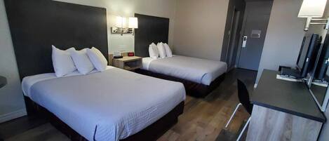 Une chambre d’hôtel avec deux lits, un bureau et une chaise.