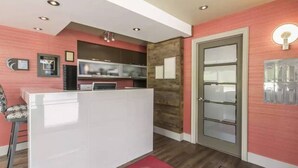 Un espace d’accueil avec un comptoir blanc, un téléviseur et un mur décoratif en bois.
