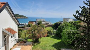 A coastal residential area with houses, a grassy yard, and a view of the sea.