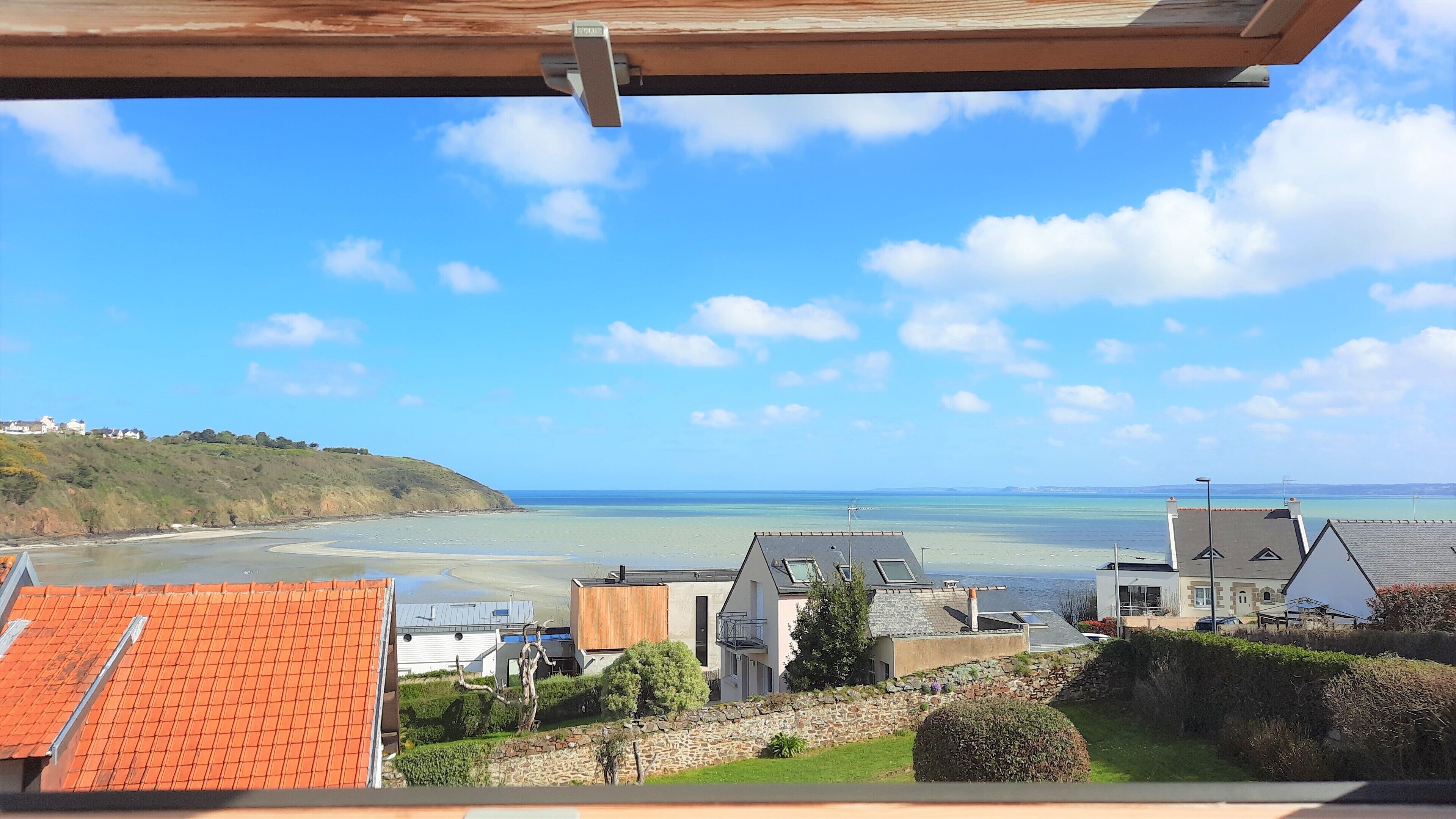 A coastal view with houses, a clear sky, and a calm sea.