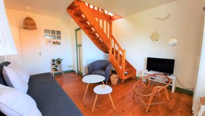 A living room with a sofa, a small table, a chair, a TV, and a wooden staircase.