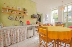 Una cocina con comedor, que incluye un lavamanos, estufa y diversos utensilios de cocina.