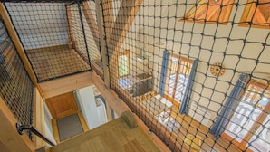 A multi-level wooden interior with a netted enclosure, wooden flooring, and a view of a room with a window and curtains. - Le Chevrais - PAISY COSDON (PAISY COSDON)