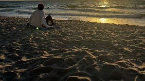 A person sitting on a sandy beach facing the ocean during sunset. - Beautiful Oceanview Modern Hotel Room W/ Balcony (Fort Lauderdale)