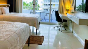 A hotel room with two beds, a desk, and a view of a building and palm trees. - Beautiful Oceanview Modern Hotel Room W/ Balcony (Fort Lauderdale)