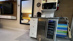 A modern kitchen with a built-in microwave, stainless steel refrigerator, and a wine cooler. - Beautiful Oceanview Modern Hotel Room W/ Balcony (Fort Lauderdale)