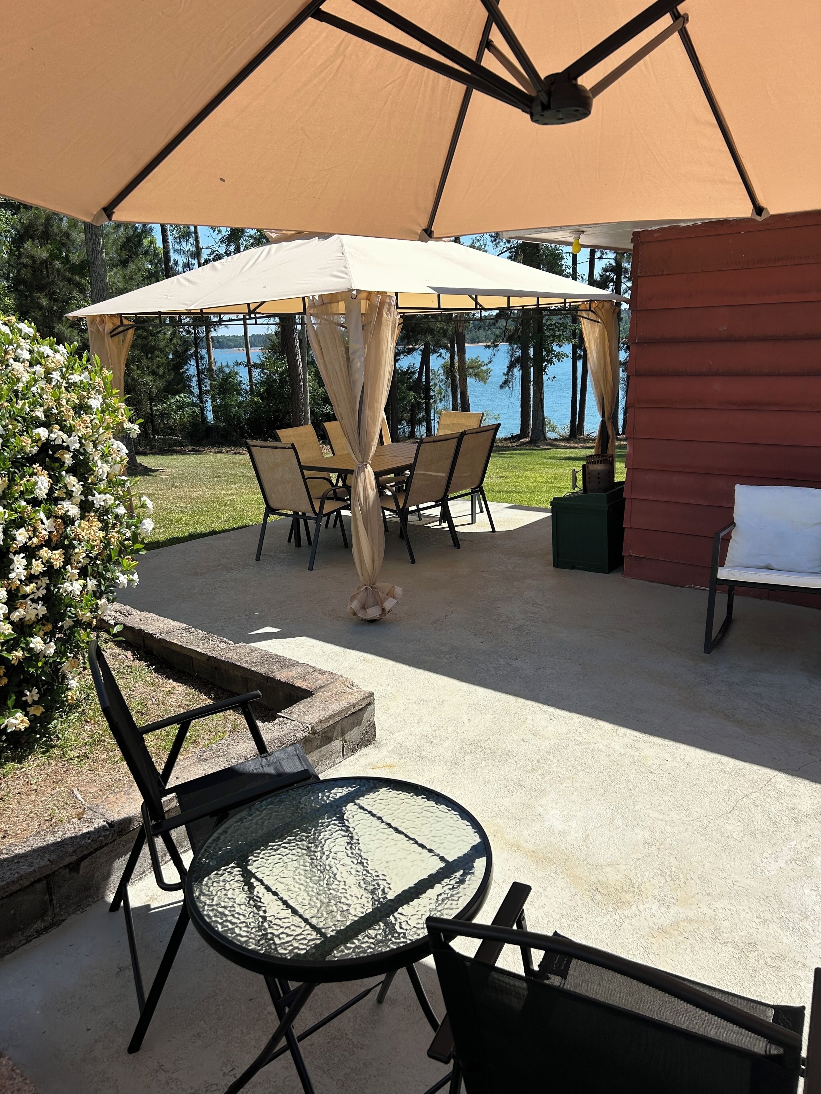 An outdoor patio with a table and chairs, a covered seating area, and a view of the water.