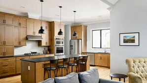 Una cocina moderna con armarios de madera, una isla central con taburetes altos e iluminación colgante.