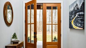Una puerta de madera con paneles de vidrio que da a un patio con árboles.