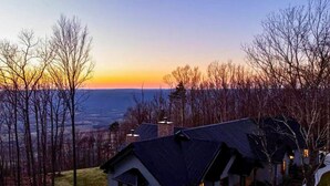 Vista de una zona residencial con casas y árboles sin hojas al atardecer.