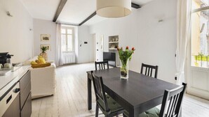 A modern kitchen with white cabinets, a black countertop, and a hanging light fixture.