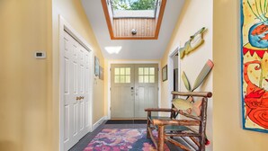 A hallway with a skylight, a wooden chair, and a colorful painting. - Beautiful Luxury Lake Front Cottage Georgian Bay (Georgian Bay)