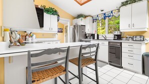 A modern kitchen with white cabinets, a central island, and a dishwasher. - Beautiful Luxury Lake Front Cottage Georgian Bay (Georgian Bay)