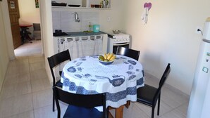 A dining area with a round table covered by a tablecloth, surrounded by chairs. A bowl of fruit is on the table. - Simple house in Cabo Frio near the beach (Cabo Frio)