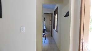A narrow hallway with a tiled floor, a door at the end, and a window on the right wall. - Simple house in Cabo Frio near the beach (Cabo Frio)
