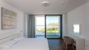 Een moderne slaapkamer met een groot bed, een bureau en uitzicht op water en bergen.