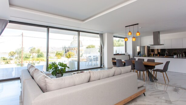 Een moderne woonkamer met een grote bank, een eethoek en een keuken.