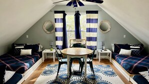 A cozy attic bedroom with a sloped ceiling, a ceiling fan, two beds with matching bedding, a round wooden table, and a patterned rug. - Lake Hartwell on McKinney Point, near Clemson! (Westminster)